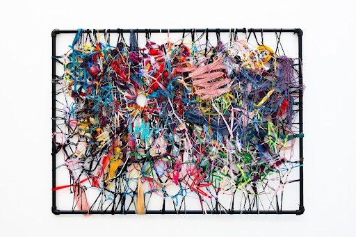 An example of Vicki's work titled 'Analysis Paralysis’.  A multicoloured tangle of fabrics attached to a scaffold frame.